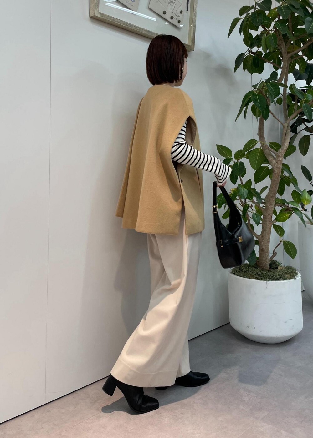 ブラック系のハンドバッグ、ベージュ系のポンチョ、ベージュ系のその他パンツを着用したレディースの秋コーディネートの2枚目の写真