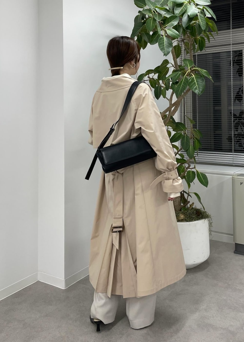 ベージュ系のスラックス、ベージュ系のトレンチコート、ブラック系のショルダーバッグを着用したレディースの冬コーディネートの3枚目の写真