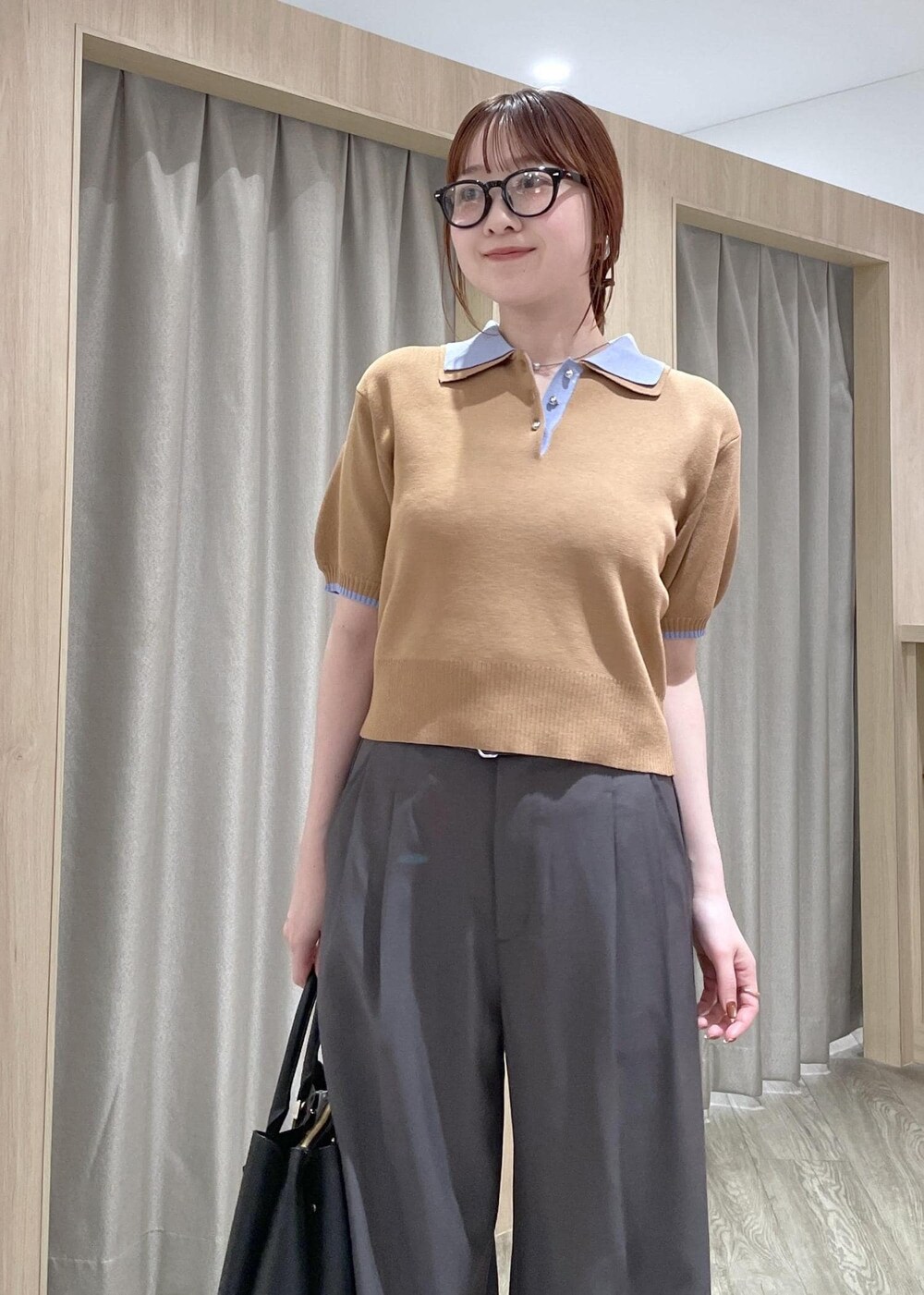 イエロー系のポロシャツ、ブラック系のトートバッグ、グレー系のその他パンツを着用したレディースの春コーディネートの5枚目の写真