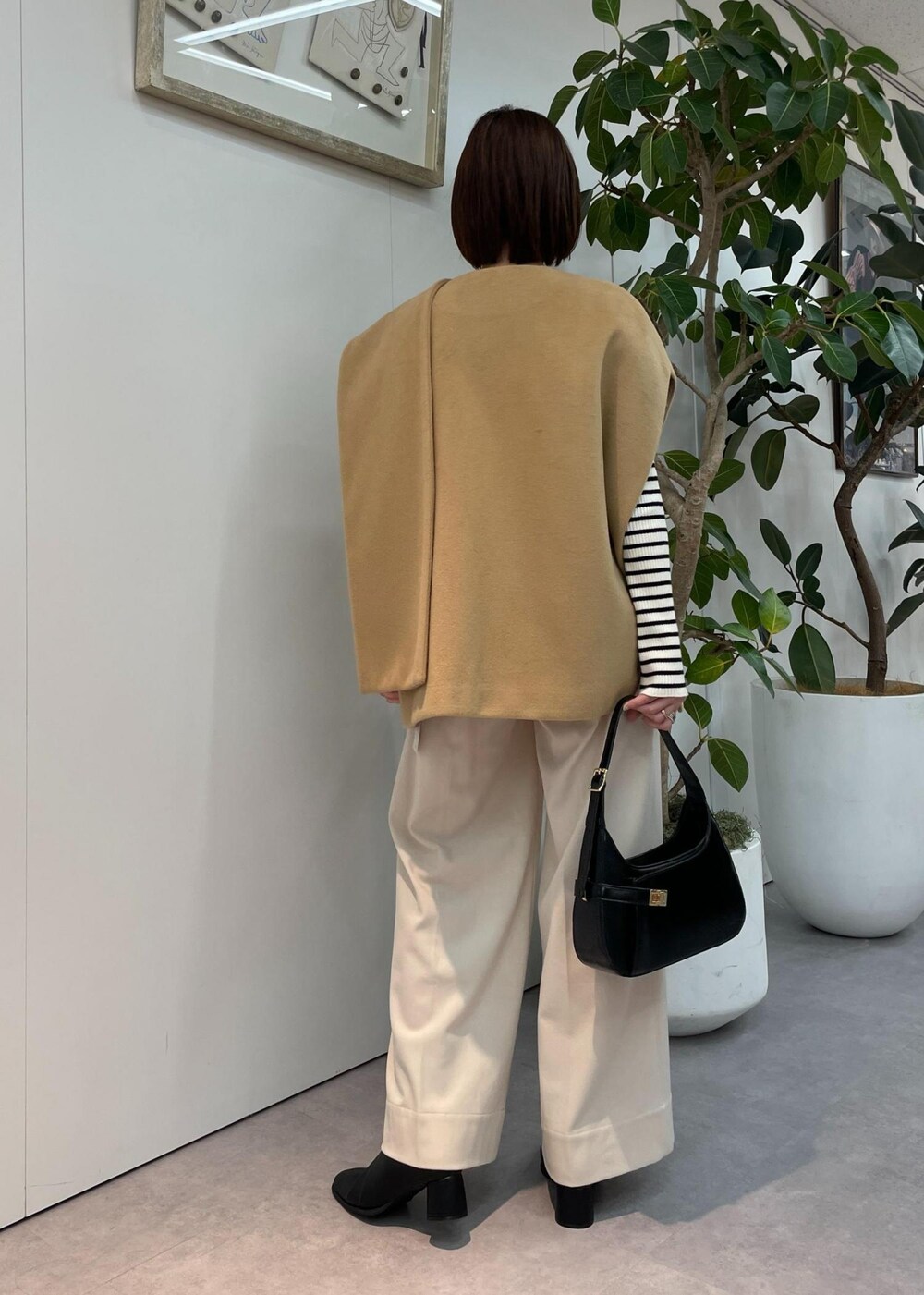 ブラック系のハンドバッグ、ベージュ系のポンチョ、ベージュ系のその他パンツを着用したレディースの秋コーディネートの3枚目の写真