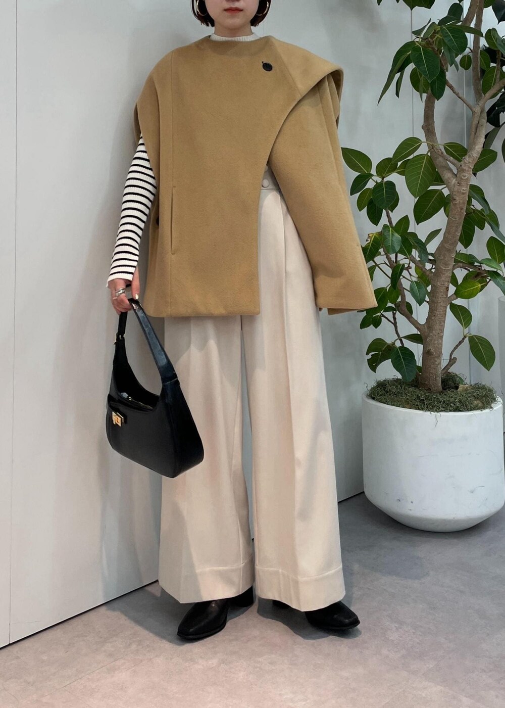 ブラック系のハンドバッグ、ベージュ系のポンチョ、ベージュ系のその他パンツを着用したレディースの秋コーディネートの4枚目の写真