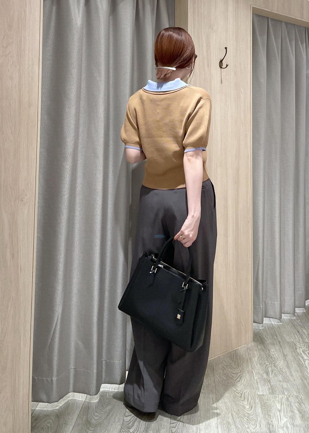 イエロー系のポロシャツ、ブラック系のトートバッグ、グレー系のその他パンツを着用したレディースの春コーディネートの3枚目の写真