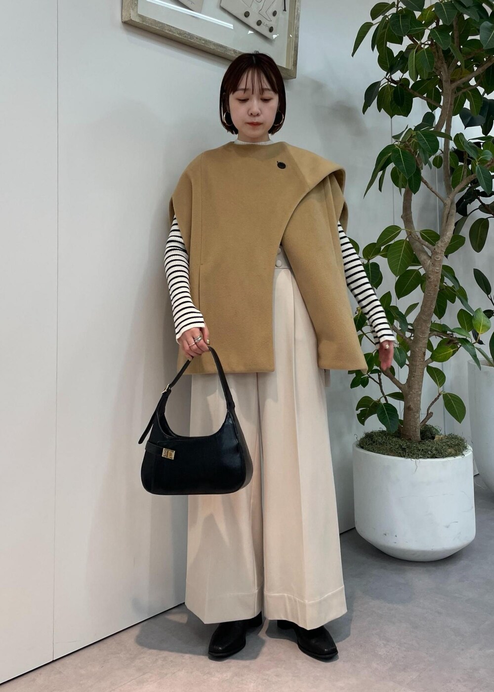 ブラック系のハンドバッグ、ベージュ系のポンチョ、ベージュ系のその他パンツを着用したレディースの秋コーディネートの6枚目の写真