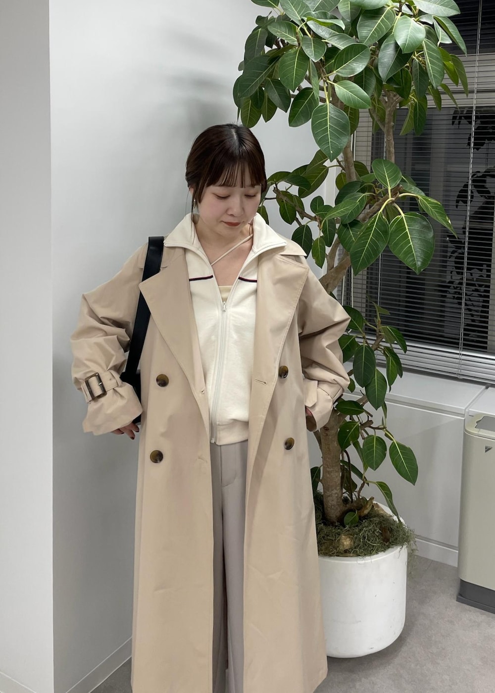 ベージュ系のスラックス、ベージュ系のトレンチコート、ブラック系のショルダーバッグを着用したレディースの冬コーディネートの4枚目の写真
