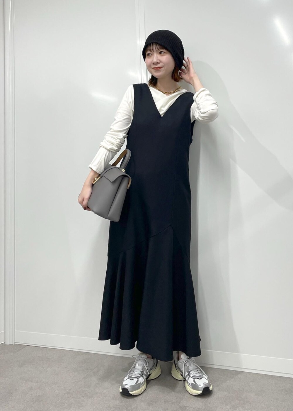 グレー系のハンドバッグ、ブラック系のワンピース、ホワイト系のTシャツ/カットソーを着用したレディースの冬コーディネートの5枚目の写真