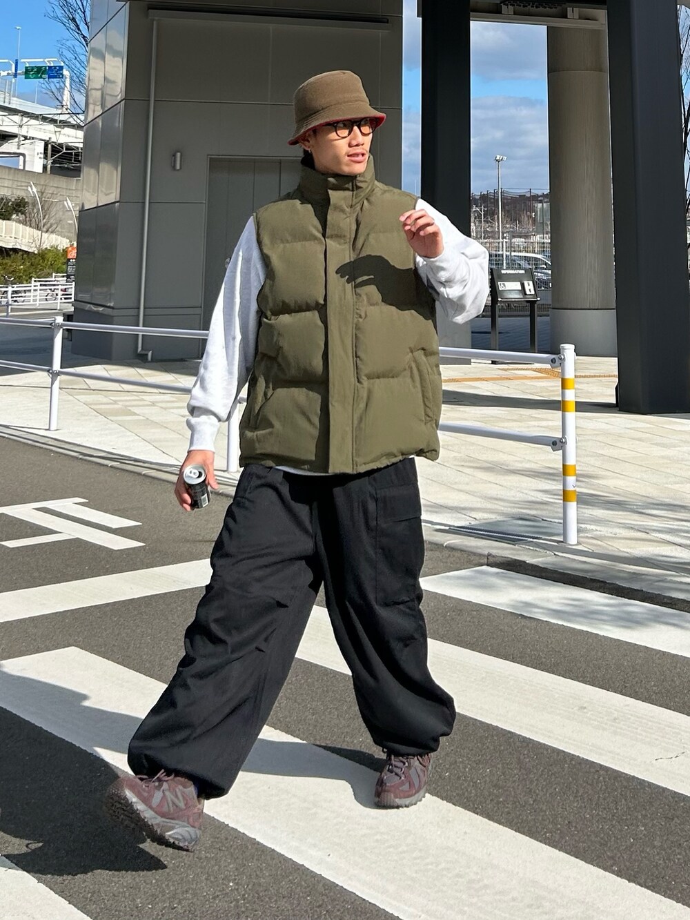 ブラック系のカーゴパンツ、ブラウン系のスニーカー、グリーン系のダウンベストを着用したメンズの冬コーディネートの2枚目の写真