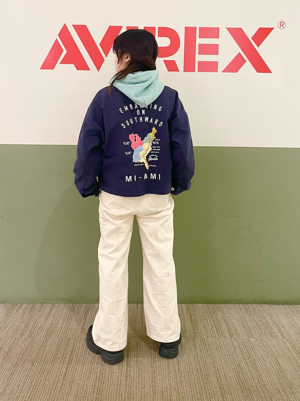 グリーン系のパーカー、ブルー系のカバーオール、ホワイト系のデニムパンツを着用したレディースの春コーディネートの2枚目の写真