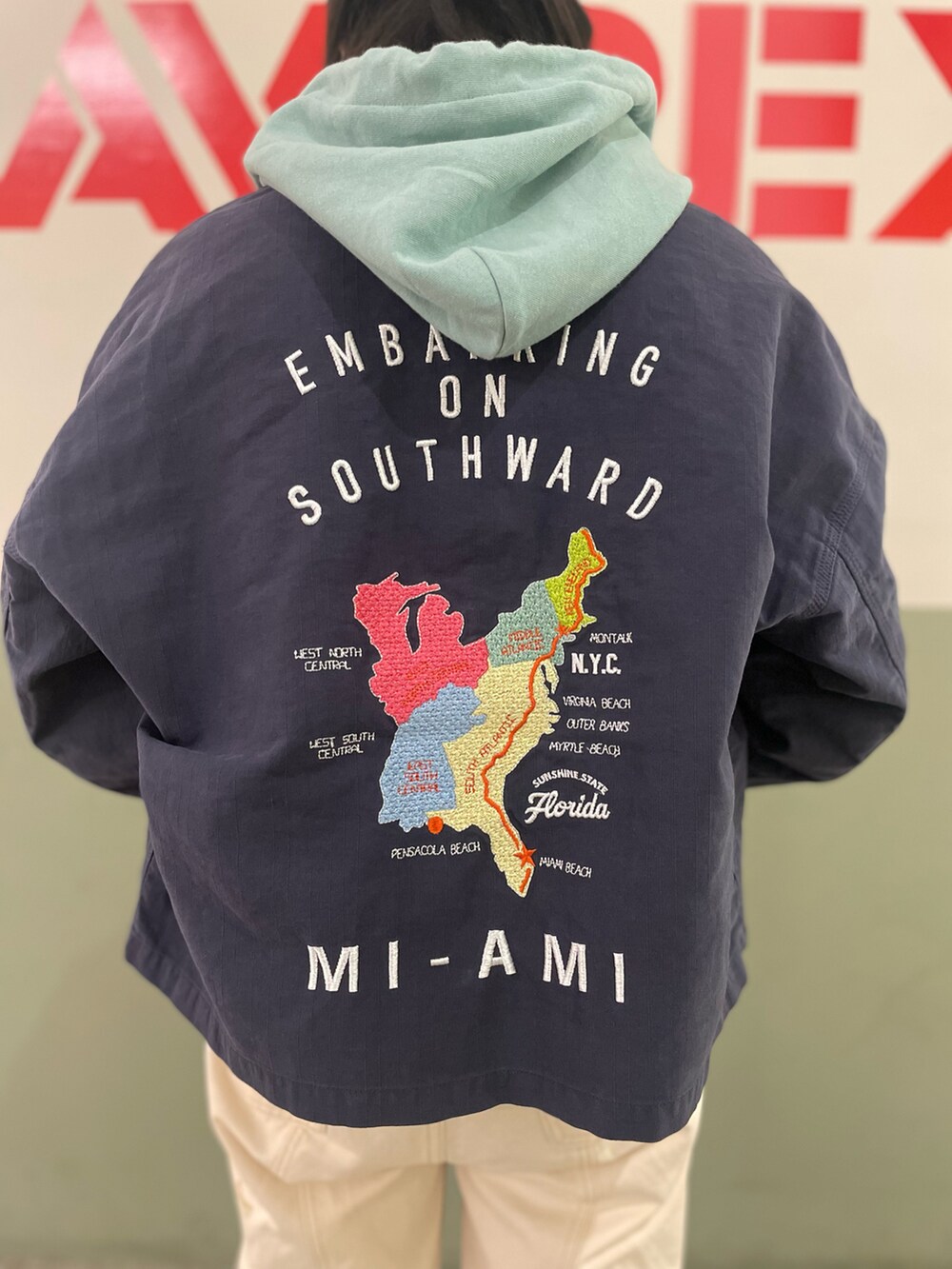 グリーン系のパーカー、ブルー系のカバーオール、ホワイト系のデニムパンツを着用したレディースの春コーディネートの3枚目の写真