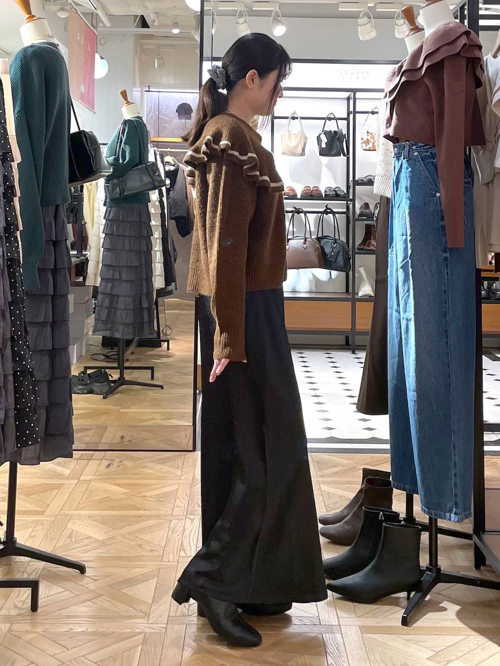 ブラック系のスカート、ブラウン系のニット/セーター、ブラック系のブーツを着用したレディースの秋コーディネートの2枚目の写真