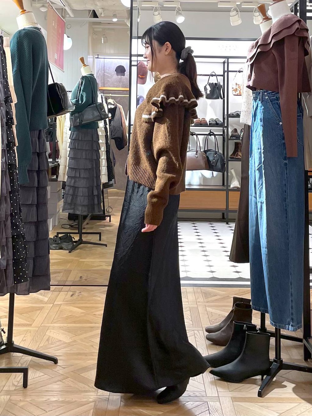 ブラック系のスカート、ブラウン系のニット/セーター、ブラック系のブーツを着用したレディースの秋コーディネートの4枚目の写真