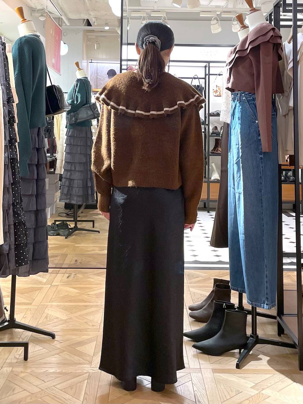 ブラック系のスカート、ブラウン系のニット/セーター、ブラック系のブーツを着用したレディースの秋コーディネートの3枚目の写真