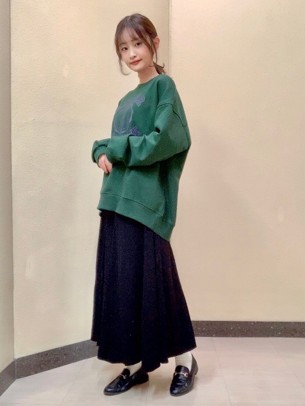 グリーン系のスウェット、ブラック系のスカートを着用したレディースの秋コーディネートの2枚目の写真
