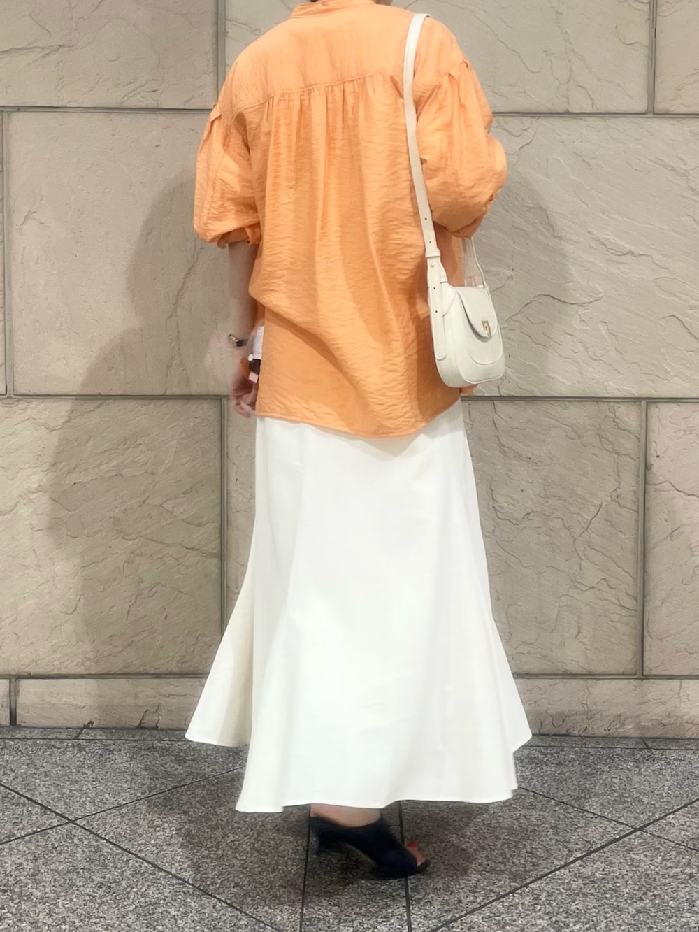 ホワイト系のスカート、オレンジ系のシャツ/ブラウス、ホワイト系のTシャツ/カットソーを着用したレディースの夏コーディネートの3枚目の写真