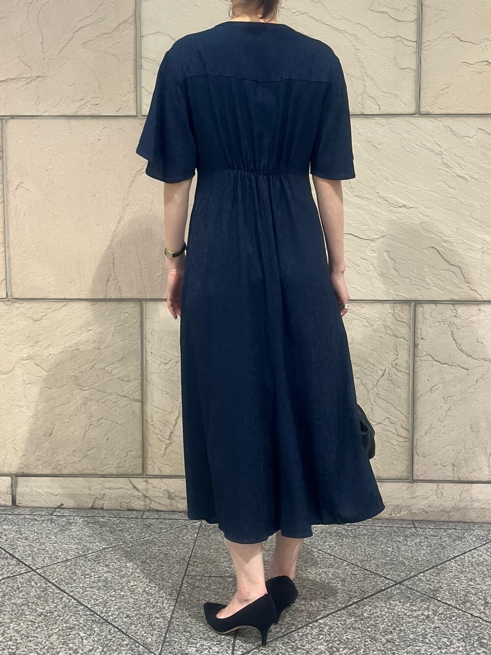 ブルー系のワンピース、ブラック系のハンドバッグ、ブラック系のパンプスを着用したレディースの夏コーディネートの2枚目の写真