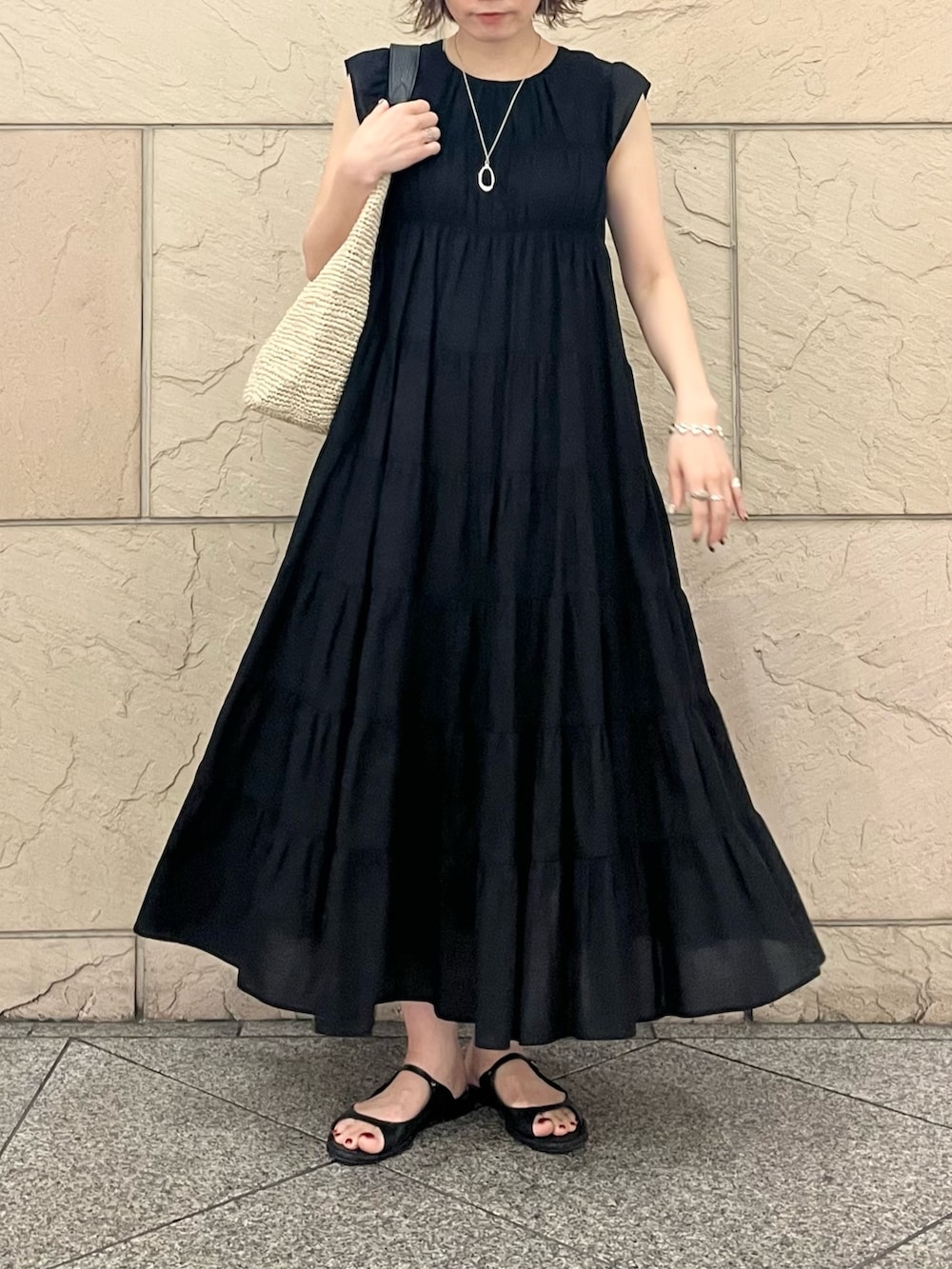 ベージュ系のかごバッグ、ブラック系のワンピース、ブラック系のサンダルを着用したレディースの夏コーディネートの4枚目の写真
