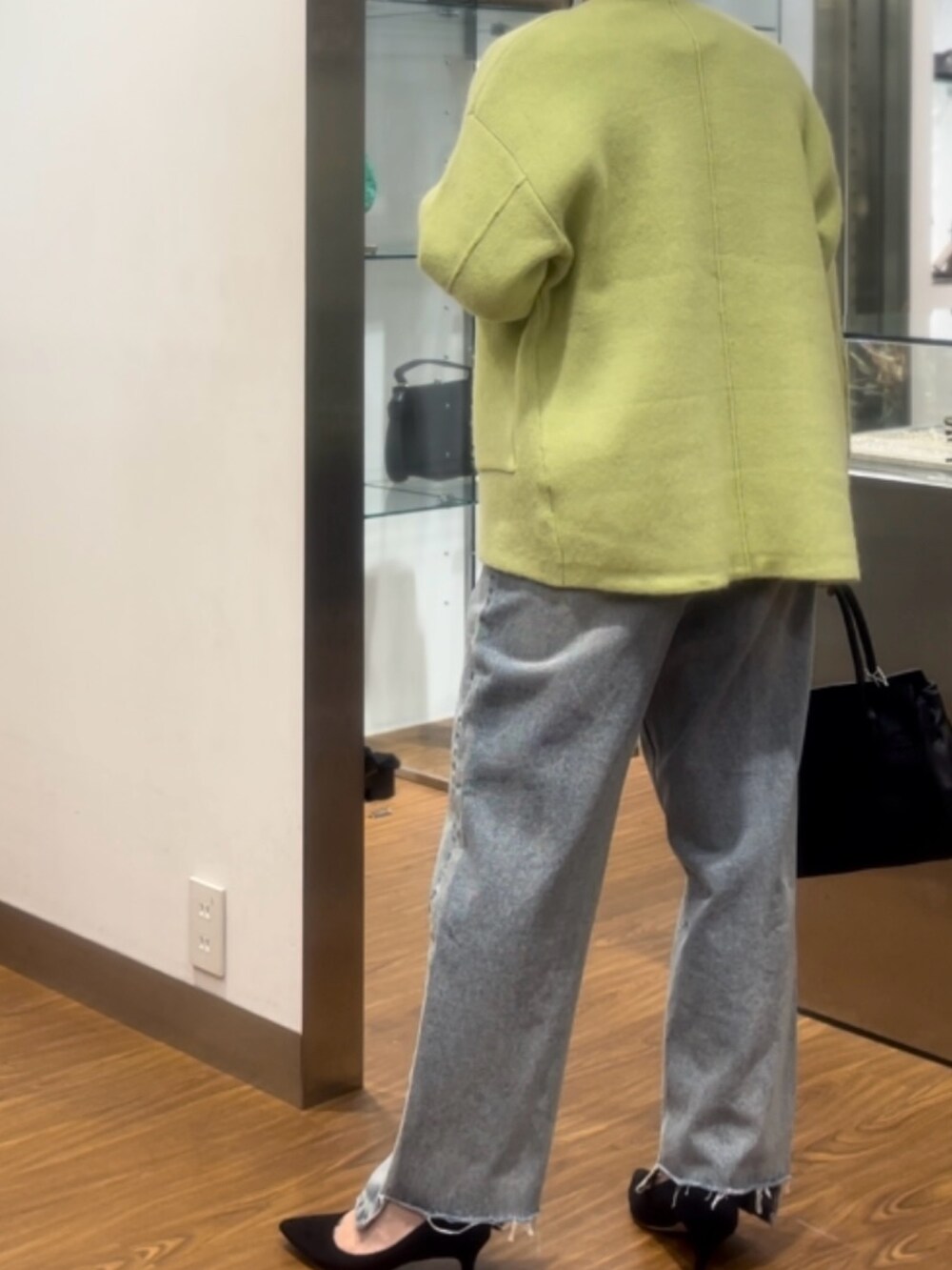 ブラック系のハンドバッグ、ブラック系のパンプス、ブルー系のデニムパンツを着用したレディースの秋コーディネートの2枚目の写真