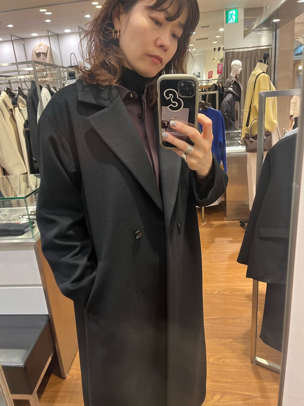 ブラック系のチェスターコート、レッド系のシャツ/ブラウス、ゴールド系のピアス（両耳用）を着用したレディースの冬コーディネートの4枚目の写真