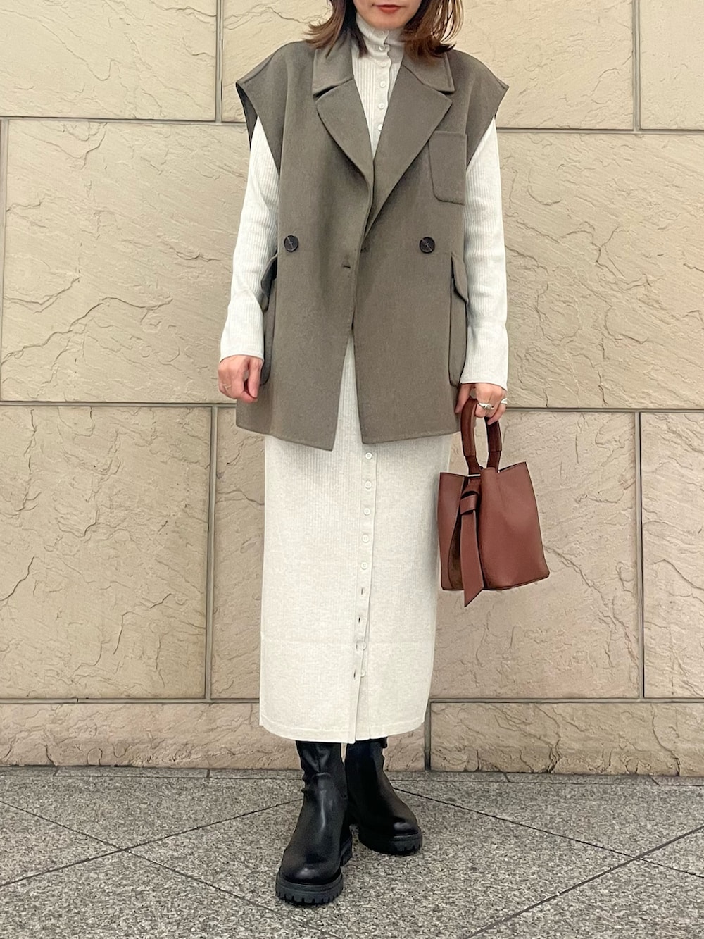 ブラウン系のハンドバッグ、ブラック系のブーツ、グリーン系のその他アウターを着用したレディースの秋コーディネートの5枚目の写真