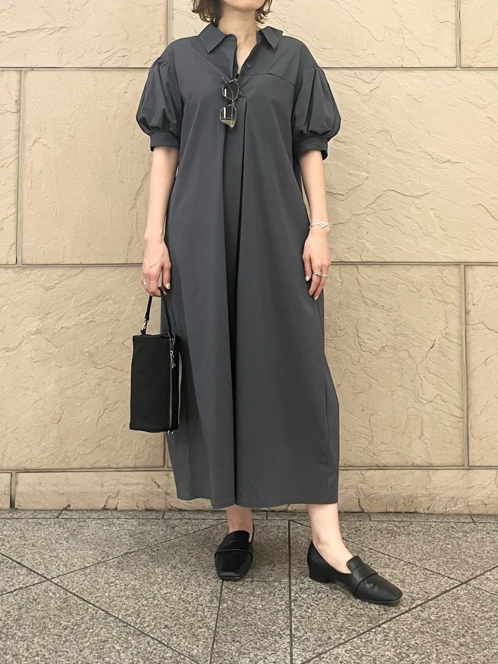 グレー系のワンピース、ブラック系のハンドバッグ、グリーン系のメガネを着用したレディースの夏コーディネートの5枚目の写真