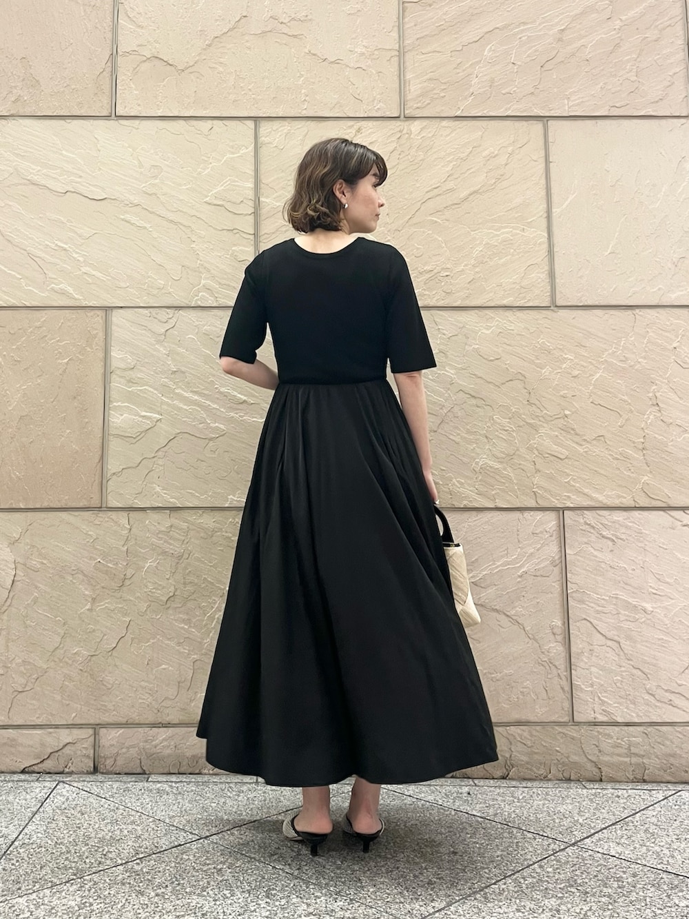 ブラック系のワンピース、ベージュ系のショルダーバッグ、ブラック系のパンプスを着用したレディースの夏コーディネートの3枚目の写真
