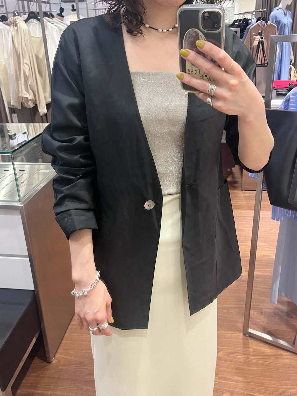 ベージュ系のキャミソール、ブラック系のノーカラージャケット、シルバー系のブレスレットを着用したレディースの春コーディネートの3枚目の写真