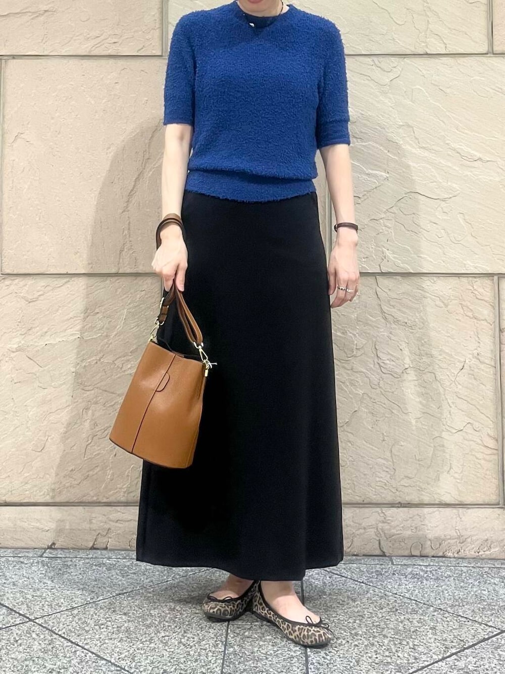 ブルー系のニット/セーター、ブラウン系のショルダーバッグ、ブラック系のスカートを着用したレディースの秋コーディネートの4枚目の写真