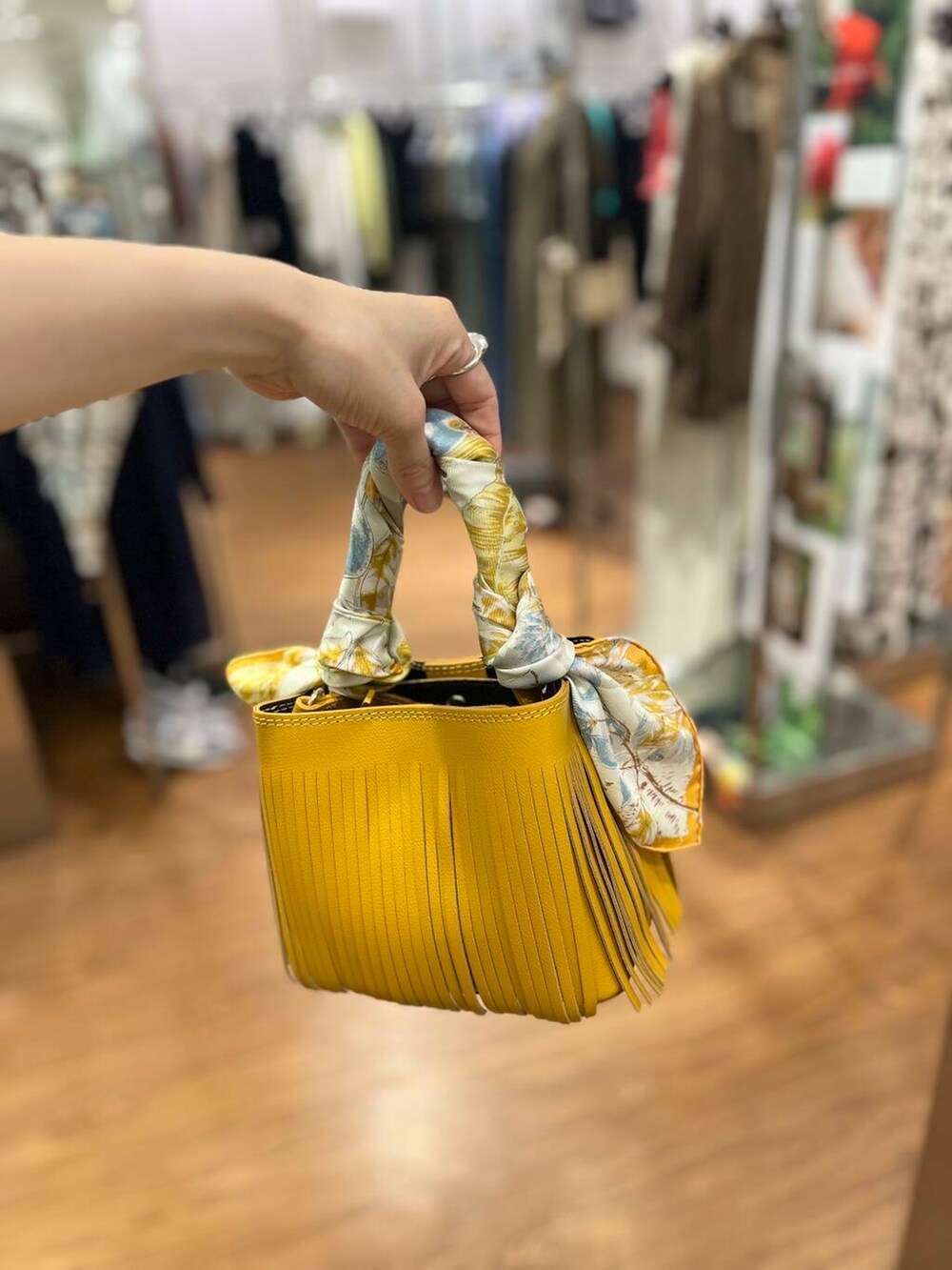 イエロー系のハンドバッグ、ブルー系のデニムパンツ、ゴールド系のTシャツ/カットソーを着用したレディースの春コーディネートの4枚目の写真