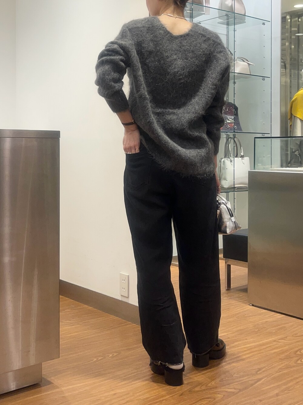 グレー系のニット/セーター、シルバー系のバッグ、ブラック系のデニムパンツを着用したレディースの秋コーディネートの2枚目の写真