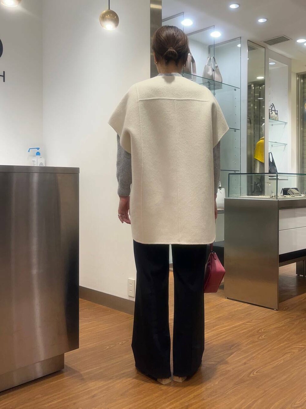 ホワイト系のポンチョ、ブラック系のその他パンツ、グレー系のニット/セーターを着用したレディースの秋コーディネートの3枚目の写真