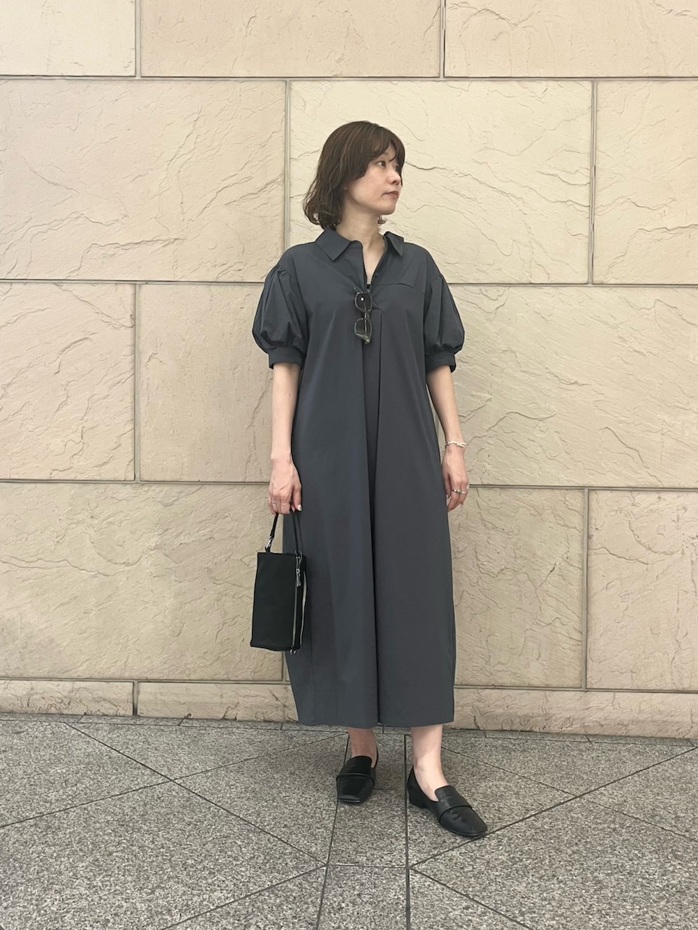 グレー系のワンピース、ブラック系のハンドバッグ、グリーン系のメガネを着用したレディースの夏コーディネートの2枚目の写真