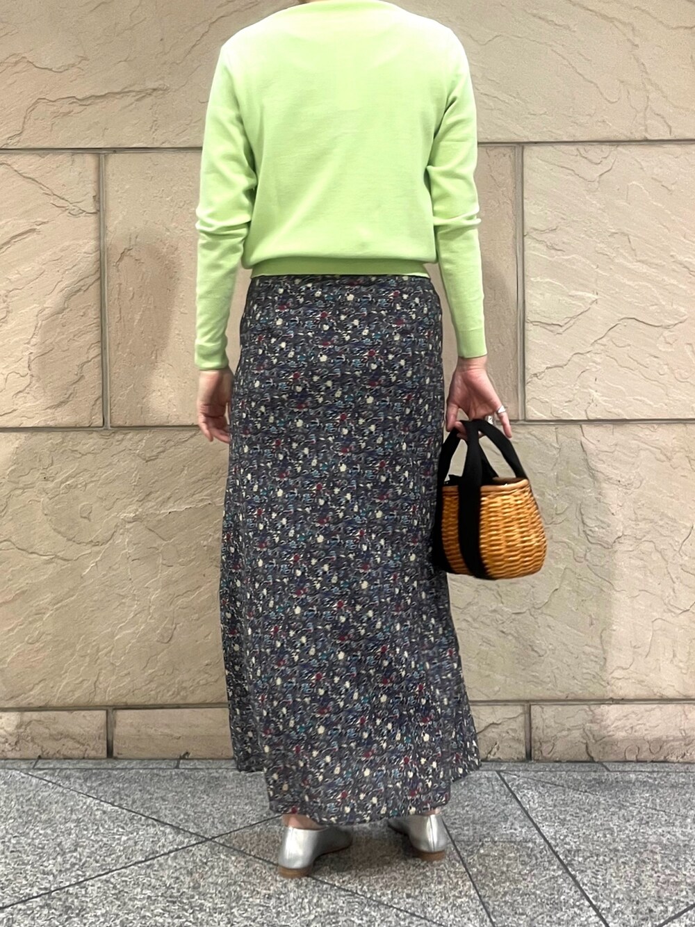 グリーン系のトップス、ブラック系のハンドバッグ、ブラック系のスカートを着用したレディースの春コーディネートの2枚目の写真