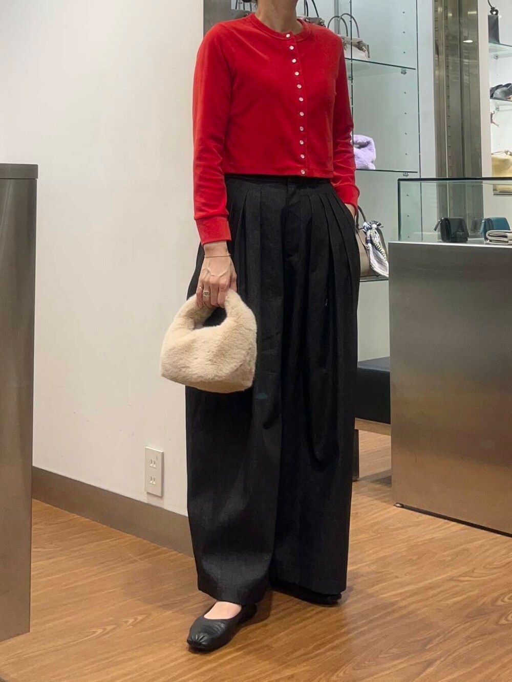 レッド系のカーディガン/ボレロ、ブルー系のチェスターコート、ブラック系のデニムパンツを着用したレディースの秋コーディネートの2枚目の写真