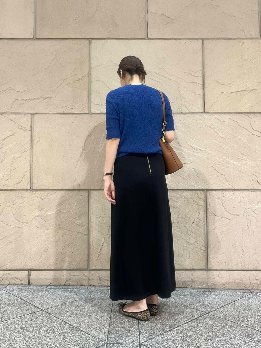 ブルー系のニット/セーター、ブラウン系のショルダーバッグ、ブラック系のスカートを着用したレディースの秋コーディネートの2枚目の写真
