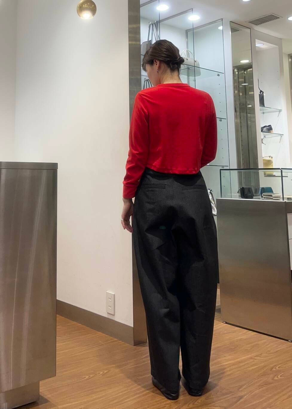 レッド系のカーディガン/ボレロ、ブルー系のチェスターコート、ブラック系のデニムパンツを着用したレディースの秋コーディネートの3枚目の写真