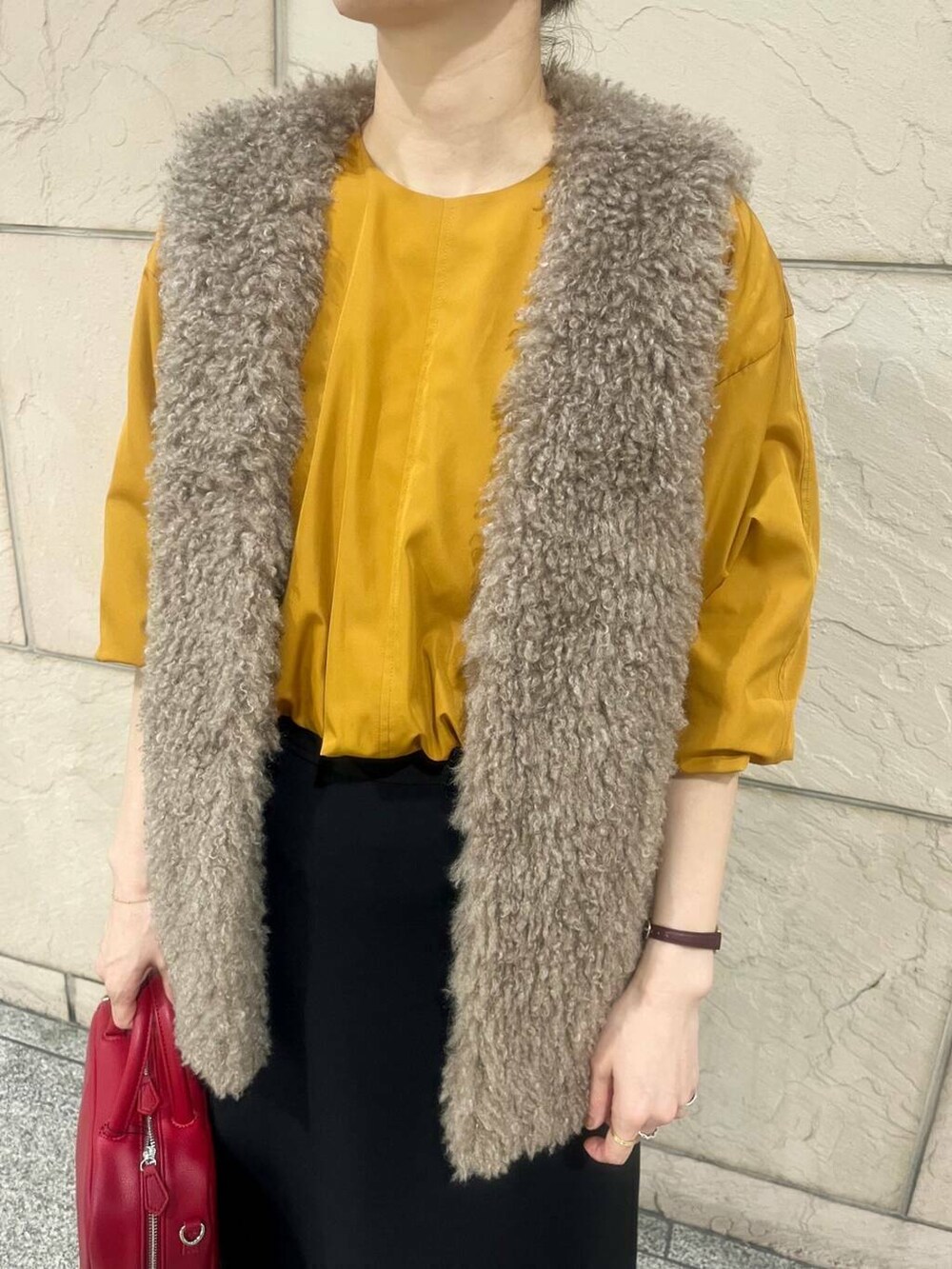 ブラウン系のベスト、オレンジ系のシャツ/ブラウス、ブラック系のスカートを着用したレディースの秋コーディネートの5枚目の写真