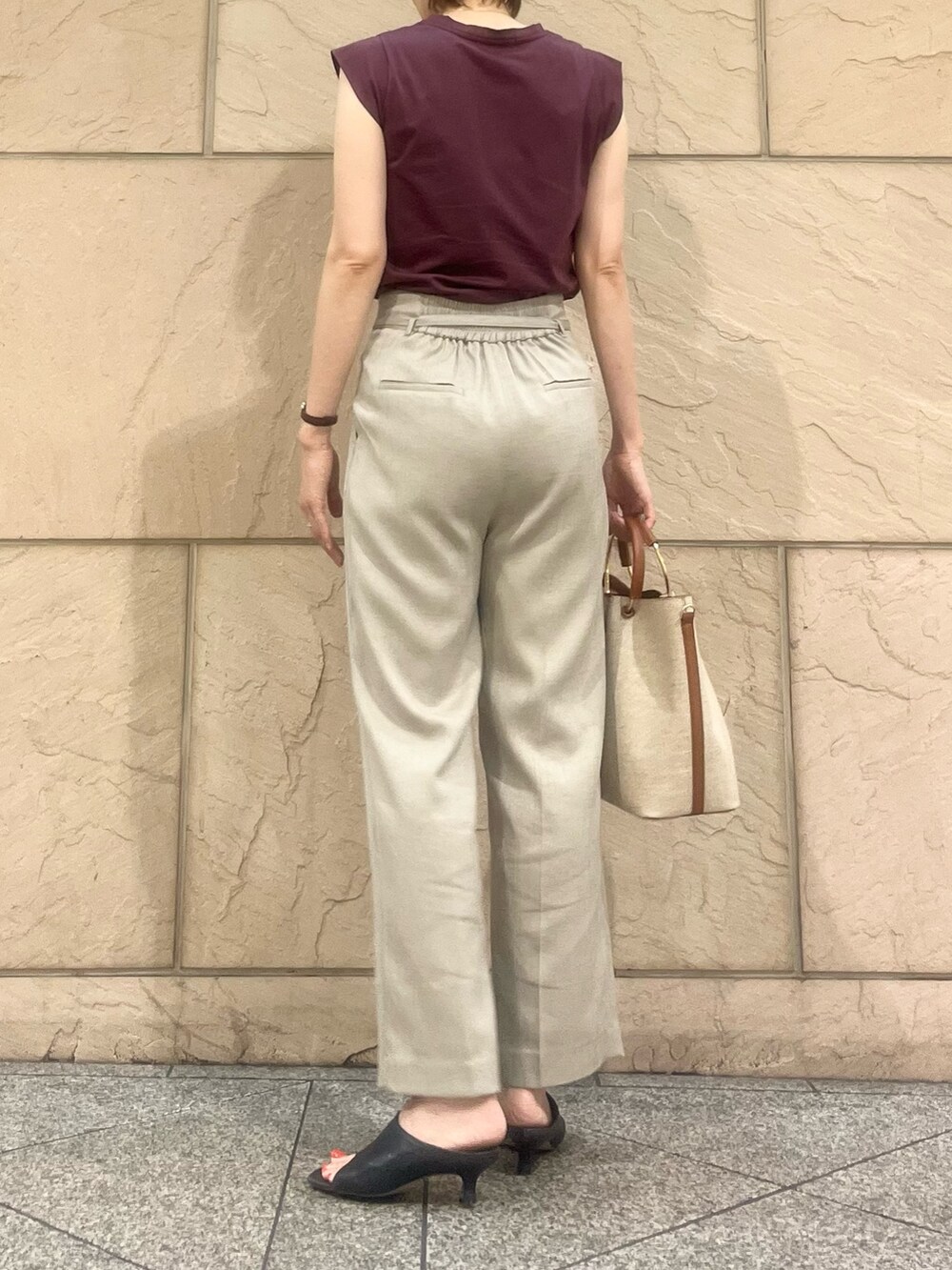 ブラウン系のハンドバッグ、ベージュ系のその他パンツ、パープル系のTシャツ/カットソーを着用したレディースの夏コーディネートの2枚目の写真