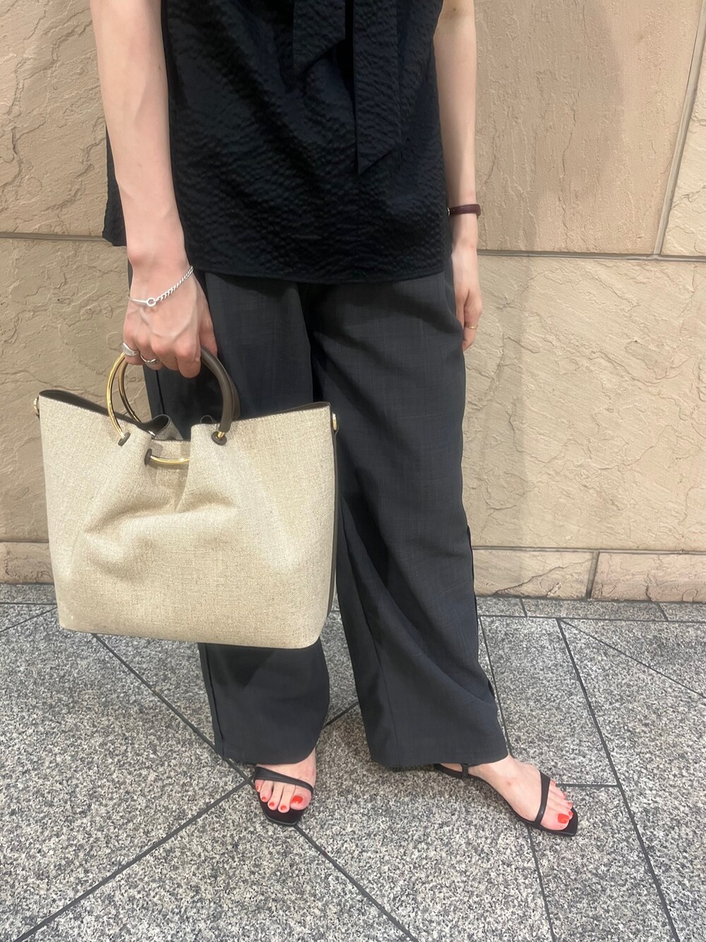 ブラウン系のハンドバッグ、ブラック系のサンダル、ブラック系のシャツ/ブラウスを着用したレディースの夏コーディネートの3枚目の写真