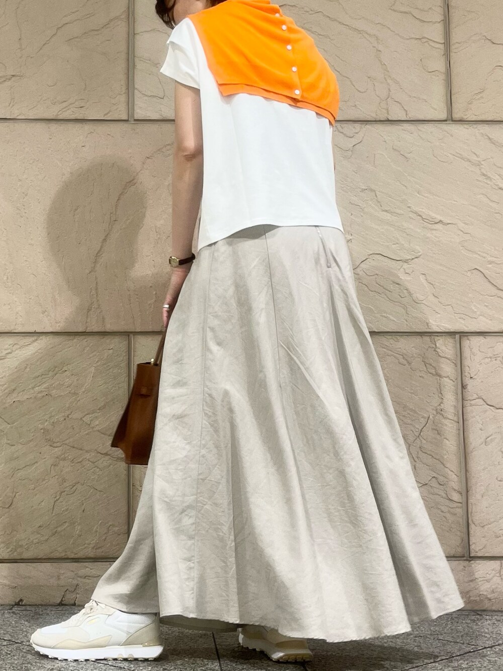 ベージュ系のスカート、ホワイト系のTシャツ/カットソー、ホワイト系のスニーカーを着用したレディースの夏コーディネートの3枚目の写真