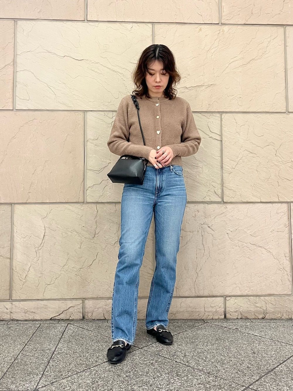 イエロー系のカーディガン/ボレロ、ブルー系のデニムパンツ、ブラック系のハンドバッグを着用したレディースの秋コーディネートの2枚目の写真