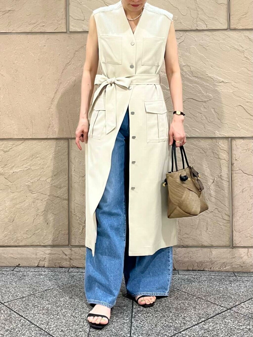 ベージュ系のワンピース、ブルー系のデニムパンツ、ベージュ系のネックレスを着用したレディースの春コーディネートの5枚目の写真