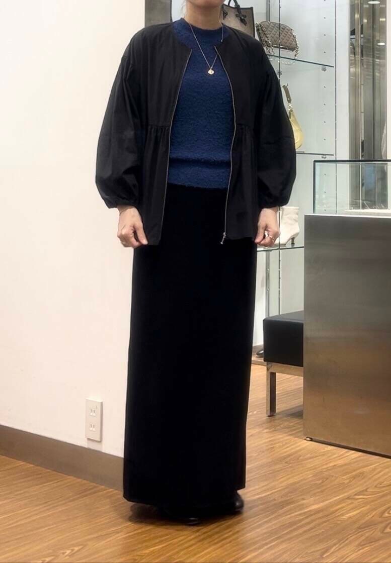 ブラック系のシャツ/ブラウス、ブルー系のニット/セーター、ベージュ系のハンドバッグを着用したレディースの秋コーディネートの3枚目の写真