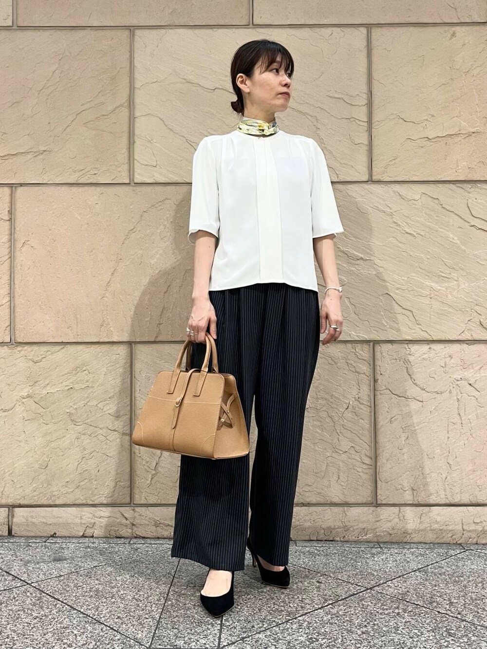 ブラック系のパンプス、ホワイト系のシャツ/ブラウス、イエロー系のトートバッグを着用したレディースの夏コーディネートの2枚目の写真