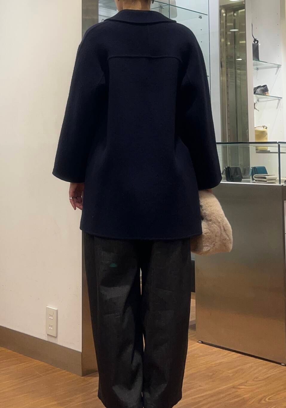 レッド系のカーディガン/ボレロ、ブルー系のチェスターコート、ブラック系のデニムパンツを着用したレディースの秋コーディネートの6枚目の写真