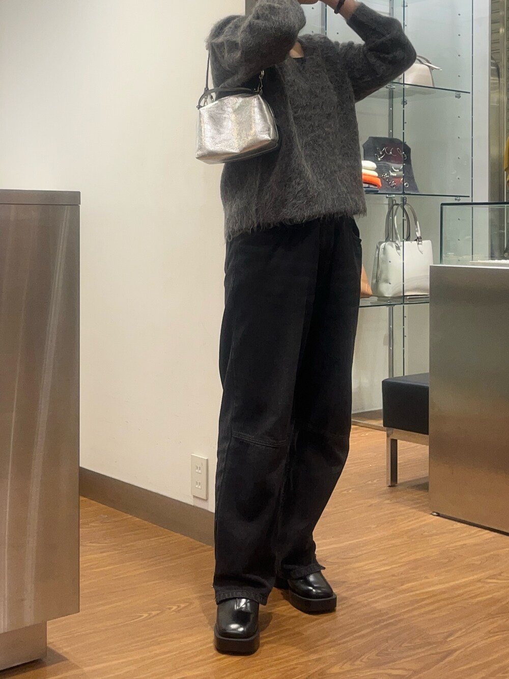 グレー系のニット/セーター、シルバー系のバッグ、ブラック系のデニムパンツを着用したレディースの秋コーディネートの3枚目の写真