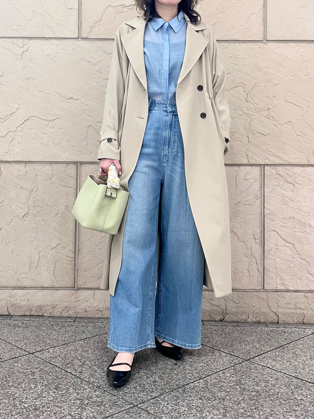 ブルー系のデニムパンツ、ベージュ系のトレンチコート、グリーン系のショルダーバッグを着用したレディースの春コーディネートの2枚目の写真