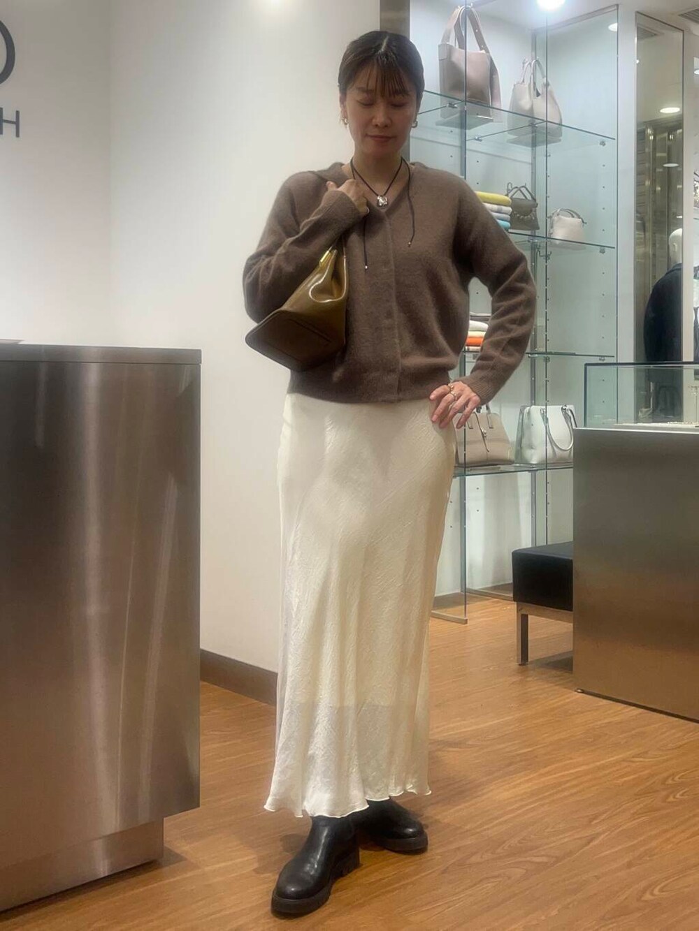 ホワイト系のスカート、イエロー系のカーディガン/ボレロ、ブラウン系のトートバッグを着用したレディースの秋コーディネートの2枚目の写真