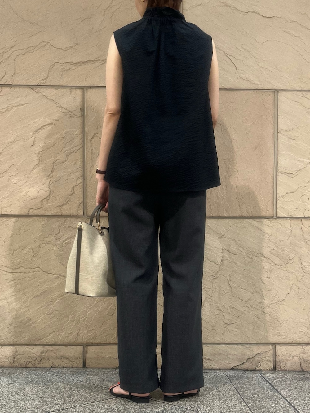 ブラウン系のハンドバッグ、ブラック系のサンダル、ブラック系のシャツ/ブラウスを着用したレディースの夏コーディネートの2枚目の写真