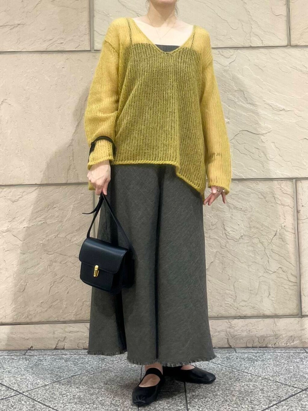 イエロー系のニット/セーター、ブラウン系のワンピース、ブラック系のショルダーバッグを着用したレディースの秋コーディネートの5枚目の写真