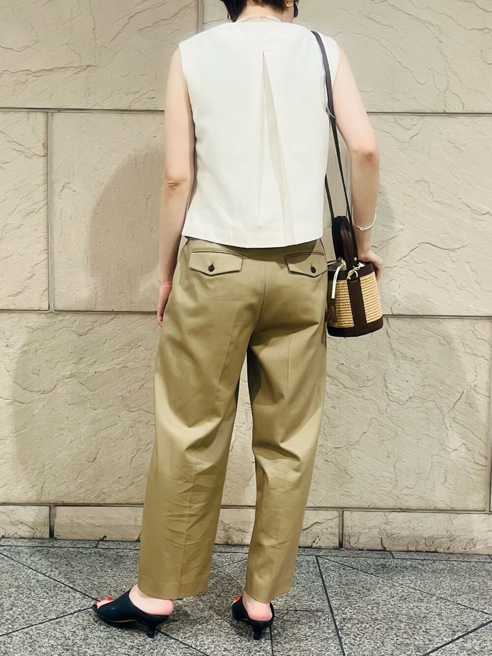 ベージュ系のその他パンツ、ブラウン系のかごバッグ、ホワイト系のベストを着用したレディースの春コーディネートの2枚目の写真