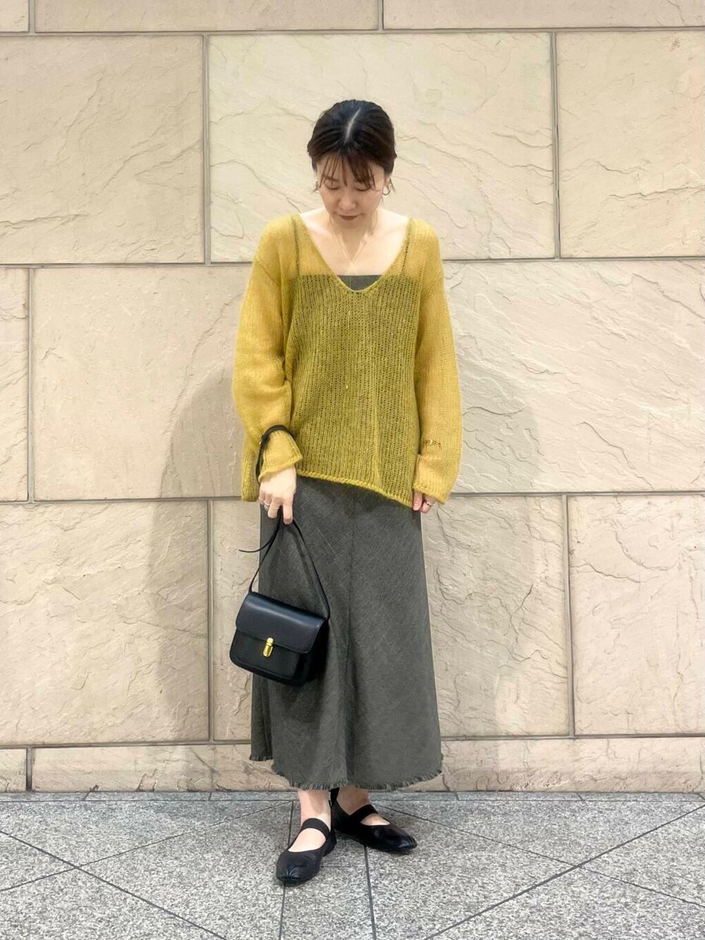 イエロー系のニット/セーター、ブラウン系のワンピース、ブラック系のショルダーバッグを着用したレディースの秋コーディネートの2枚目の写真
